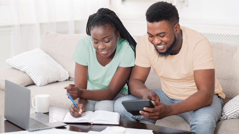 A couple looking at a calculator and laptop computer