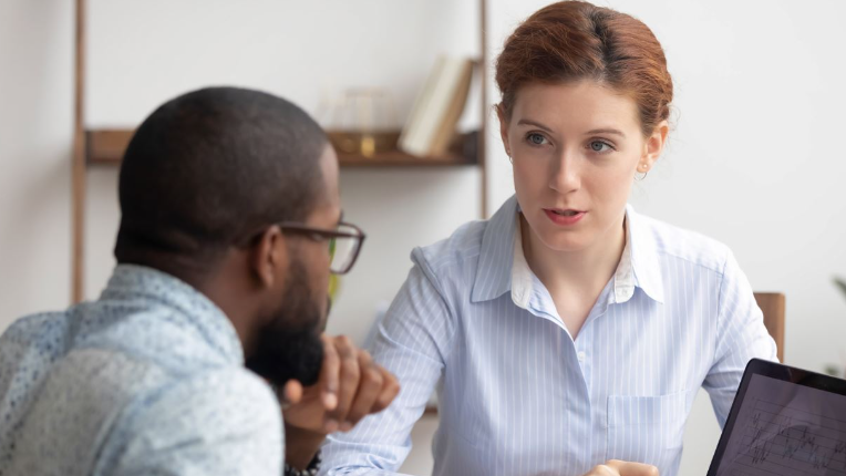 Two business people meeting at table with laptop.