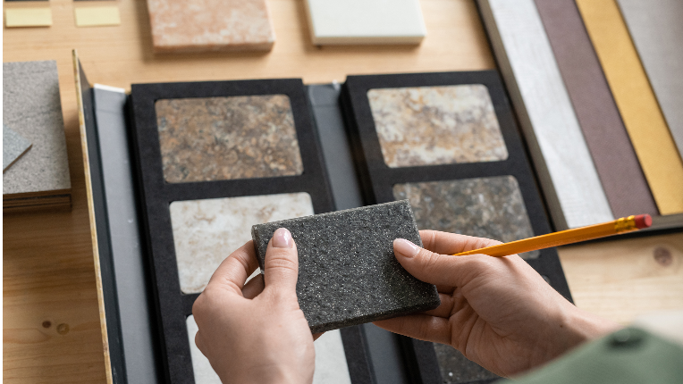 Hands of young female with pencil holding grey square marble tile