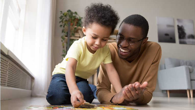 Father and little son playing jigsaw puzzle at home